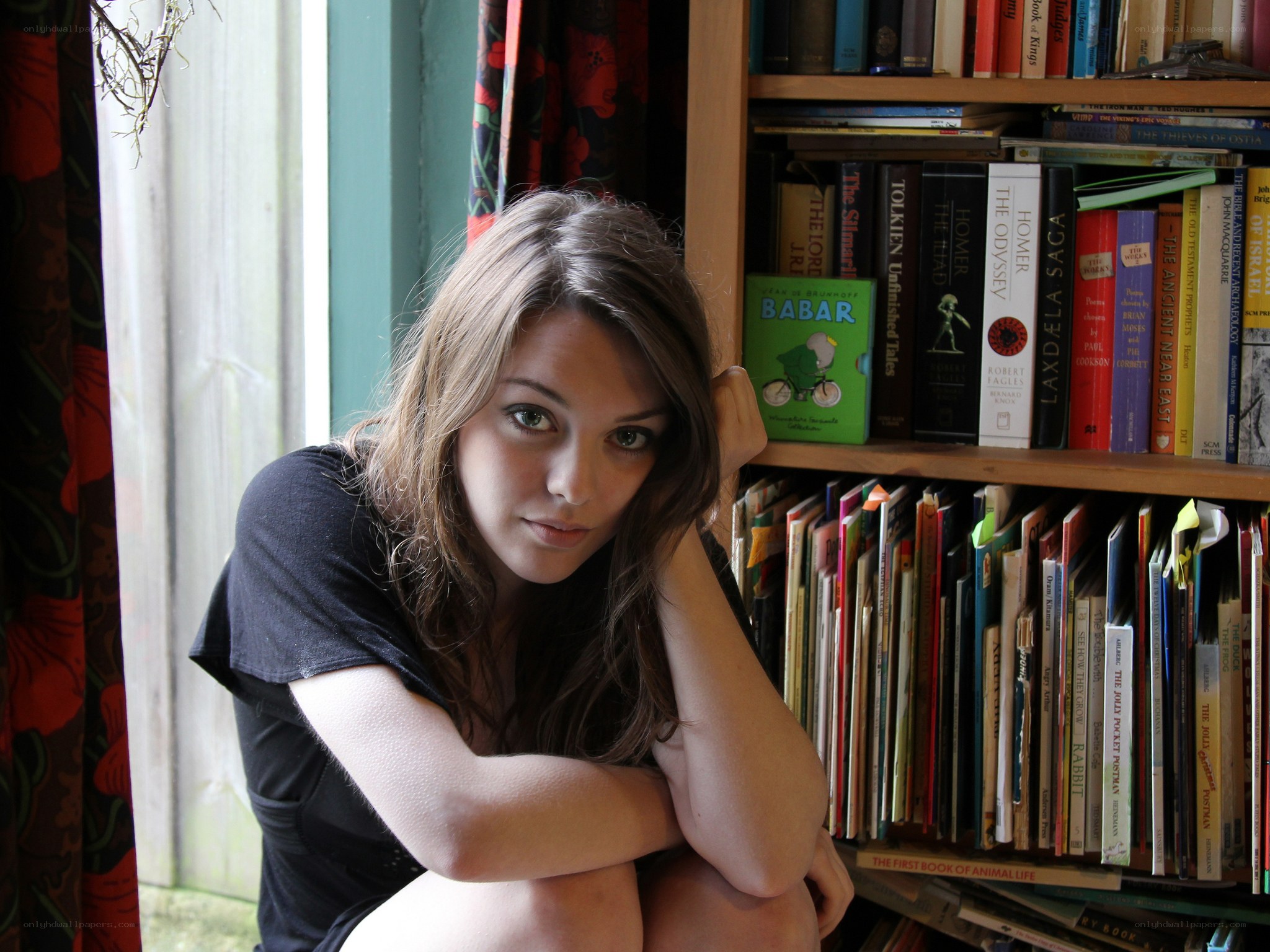 woman sitting by bookshelf