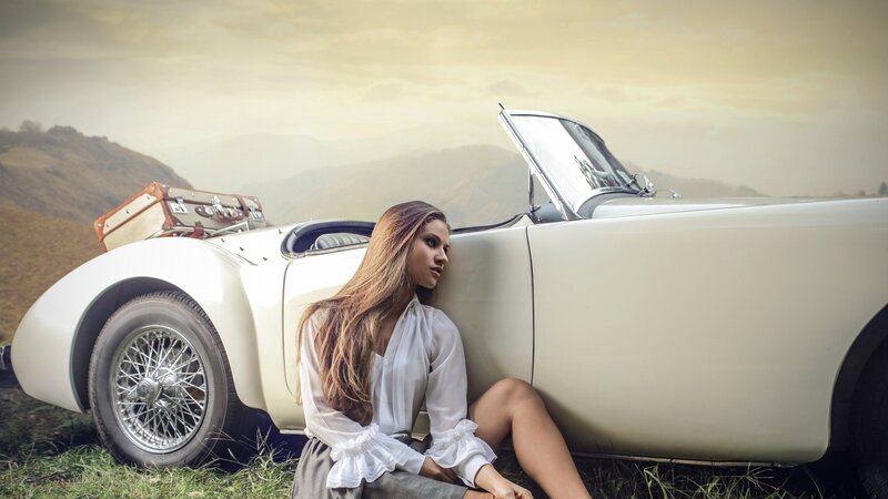 Woman Sitting by Car — White, Serene, Sunset