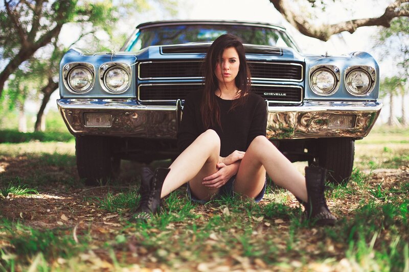 woman sitting by classic car