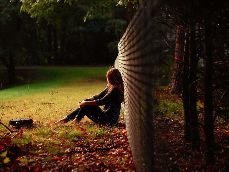 woman sitting by fence in park