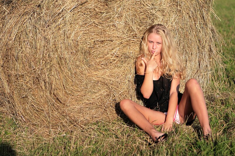 Woman sitting by hay bale