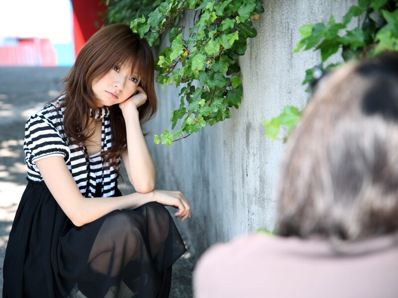 woman sitting by ivy-covered wall