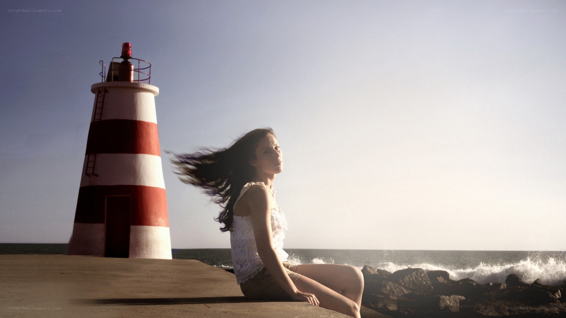 Woman sitting by lighthouse
