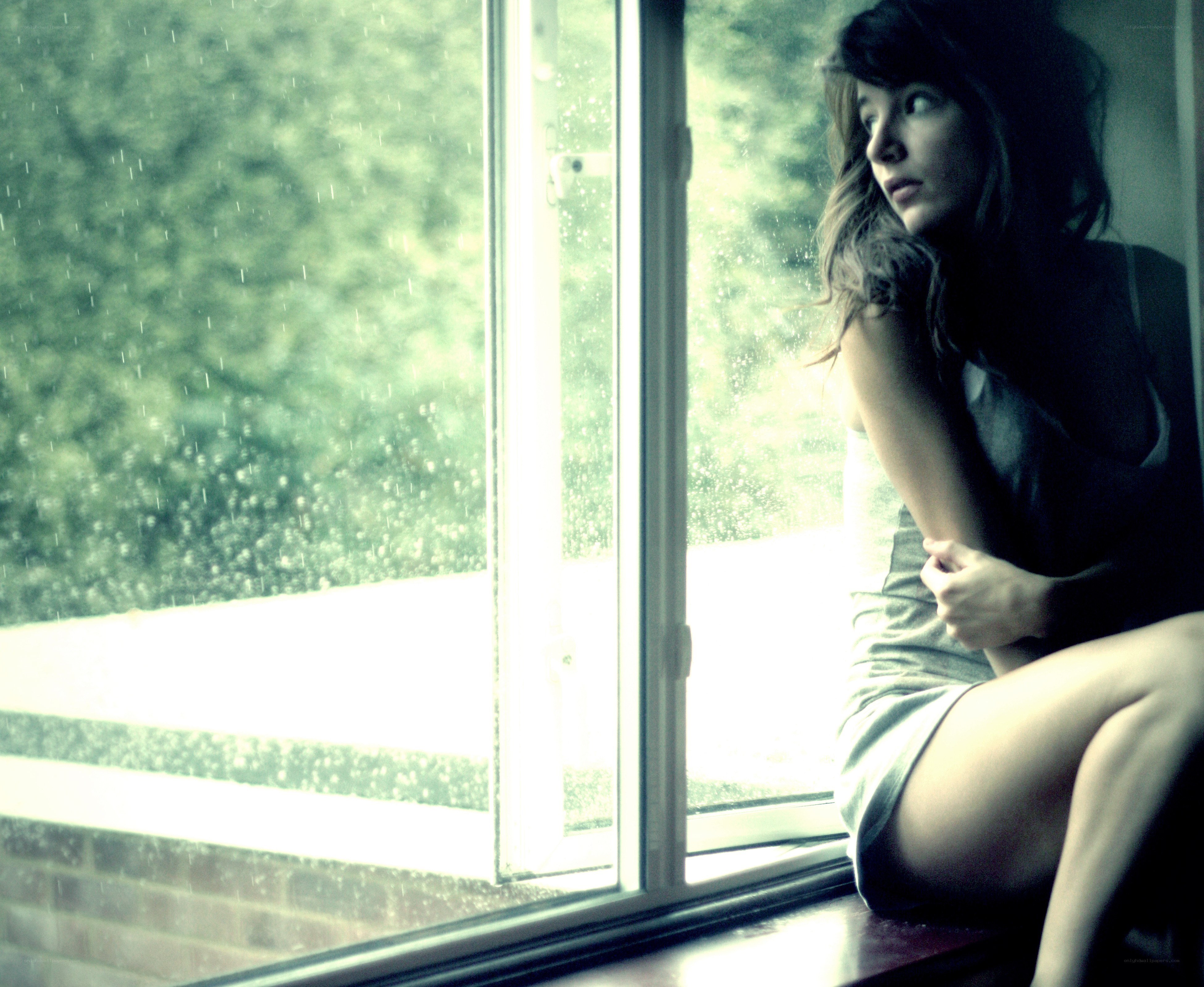 woman sitting by rainy window