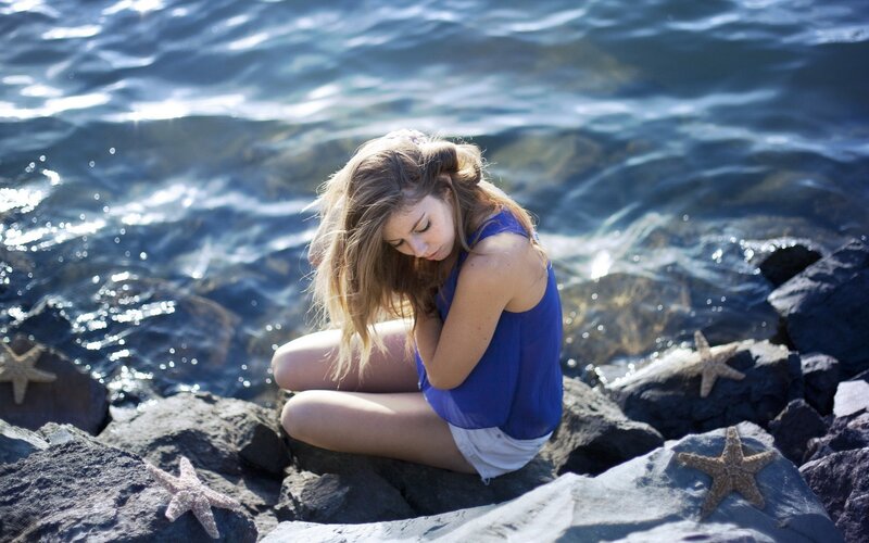 Woman sitting by the sea