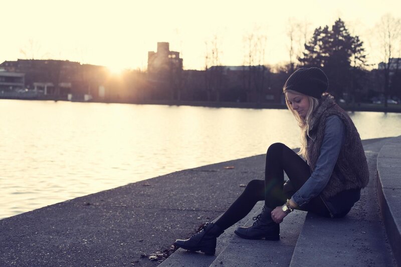 Woman sitting by the water at sunset