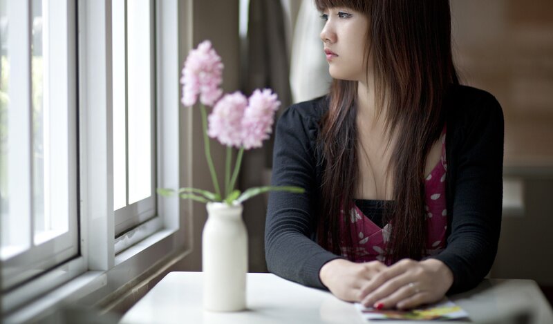 woman sitting by window with flowers