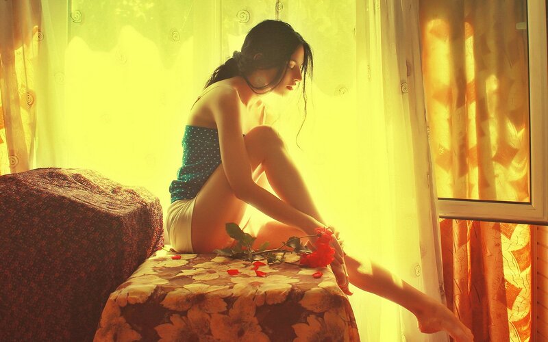 woman sitting by window with rose