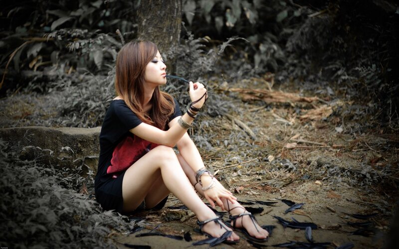 woman sitting in forest with feathers