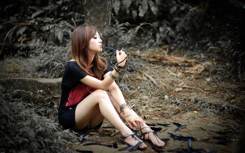 Woman sitting in forest with feathers
