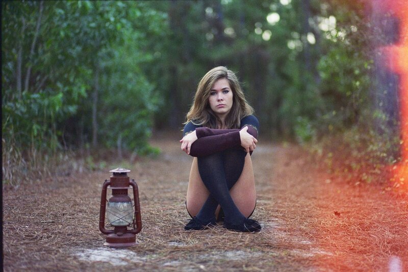 Woman sitting in forest with lantern