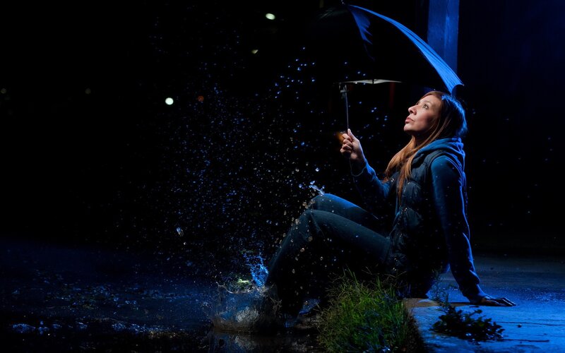 woman sitting in rain with umbrella