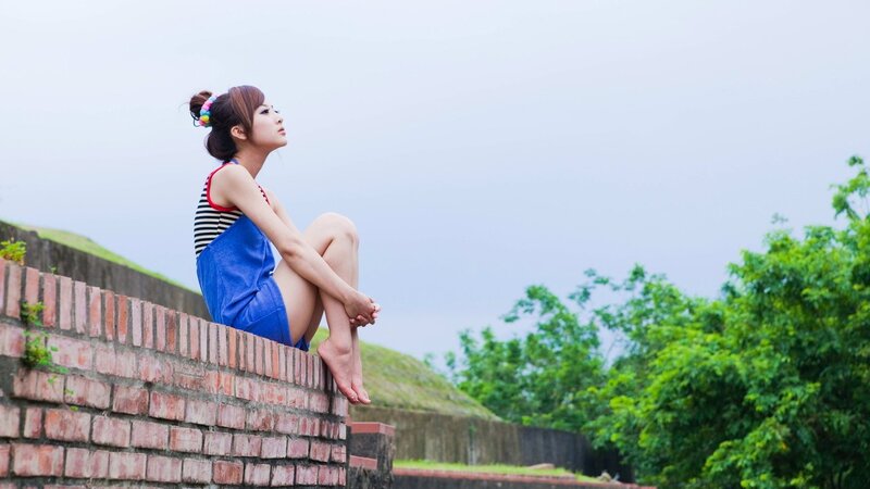 Woman sitting on a brick wall