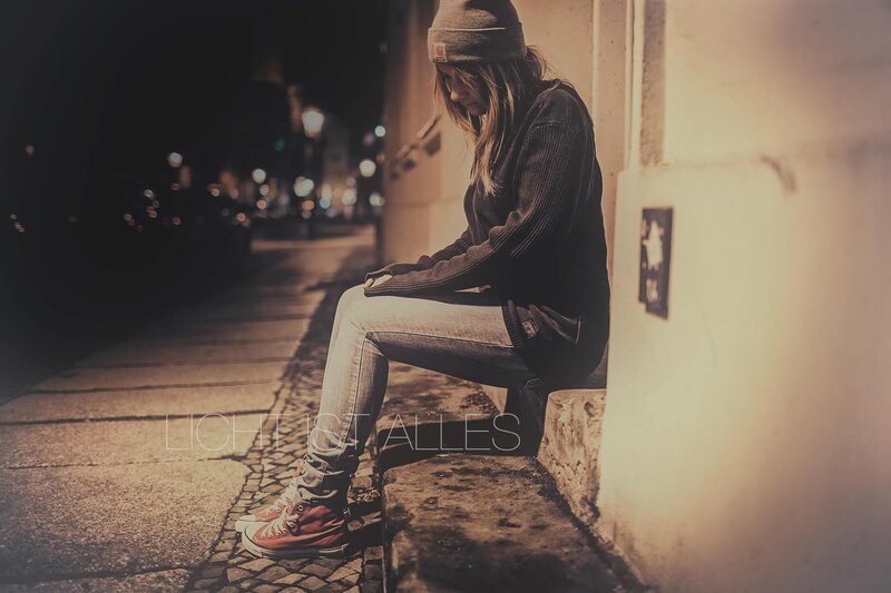 woman sitting on a curb at night