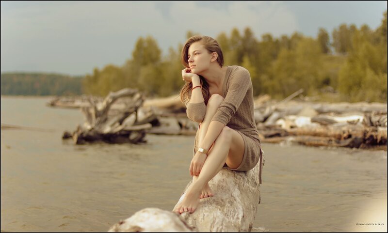 woman sitting on a log by the river