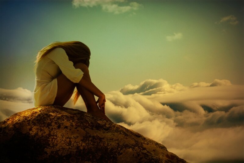 woman sitting on a rock above clouds