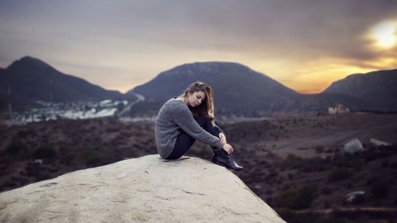Woman sitting on a rock at sunset