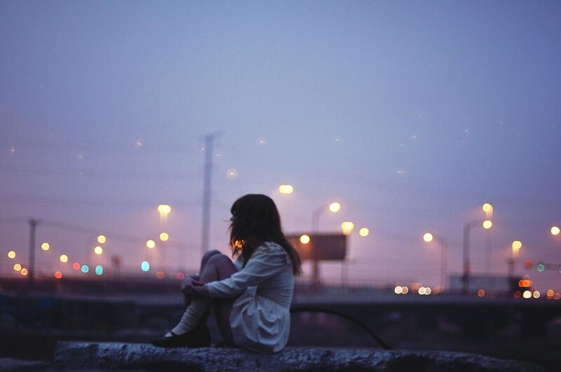 woman sitting on a wall at dusk