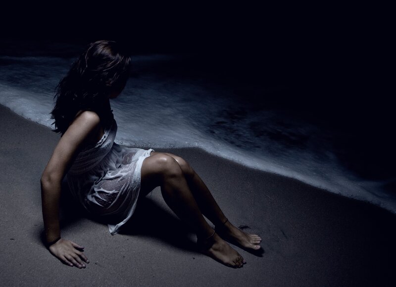 woman sitting on beach at night