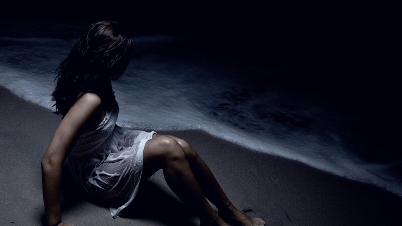 woman sitting on beach at night