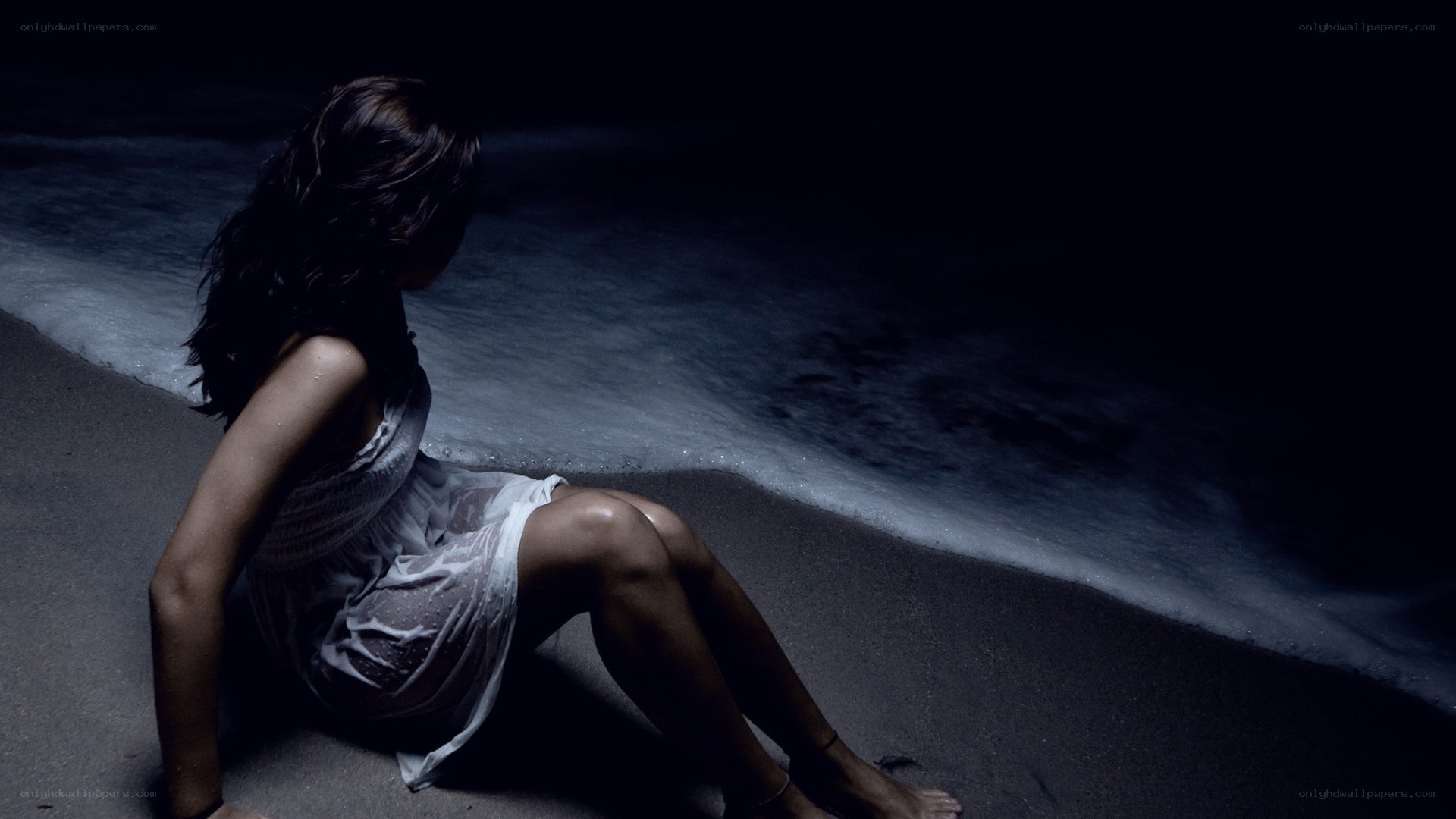 woman sitting on beach at night