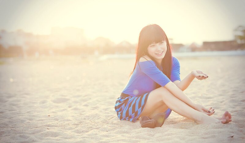 woman sitting on beach at sunset
