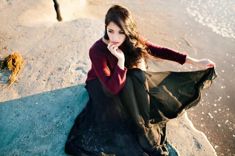 woman sitting on beach at sunset