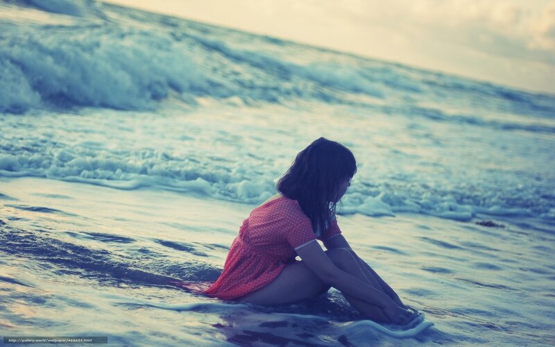 Woman sitting on beach at sunset