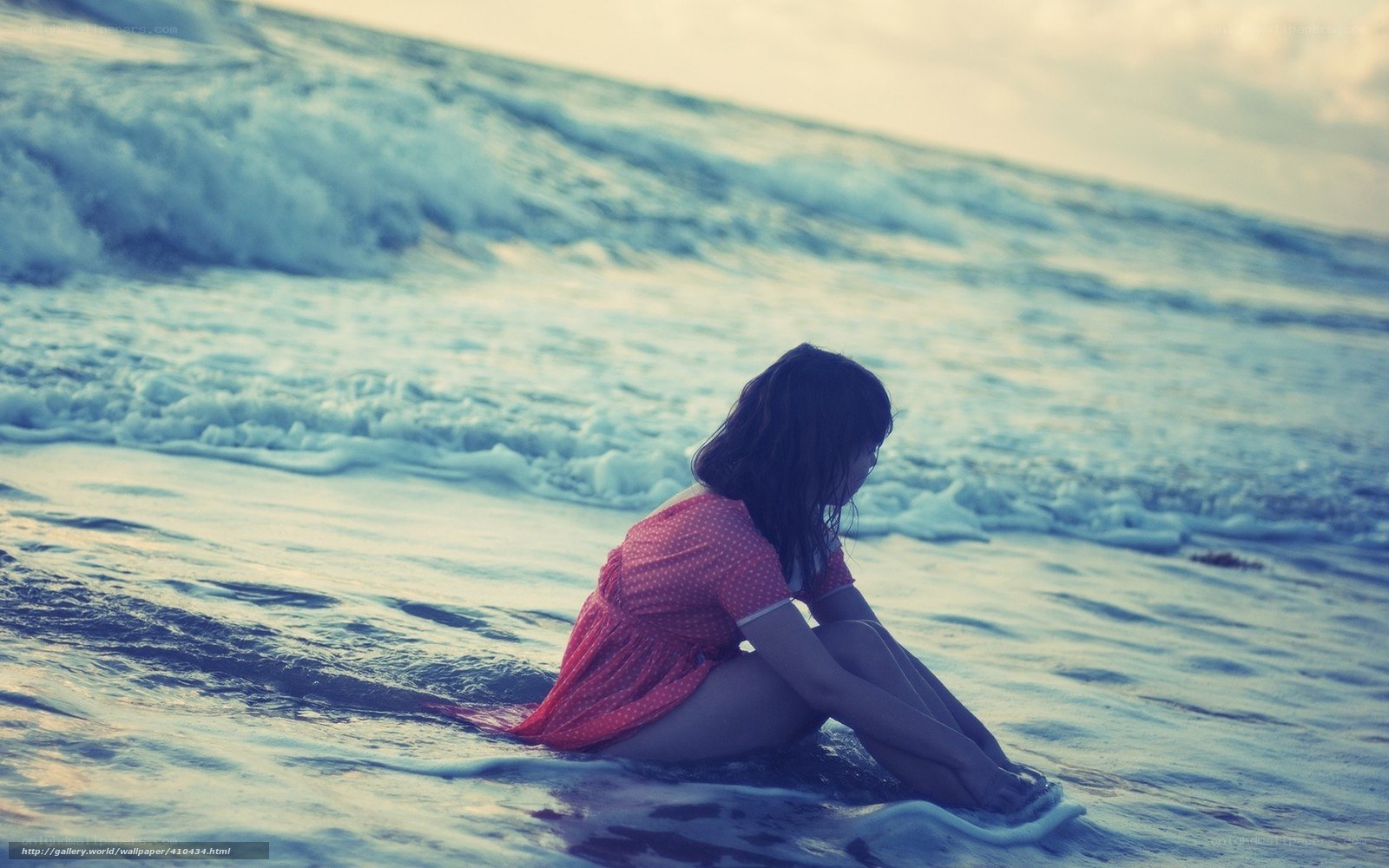 Woman sitting on beach at sunset