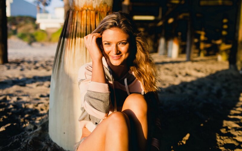 woman sitting on beach at sunset