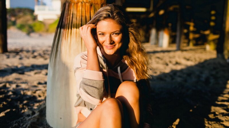 woman sitting on beach at sunset