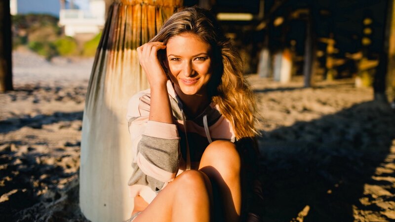 woman sitting on beach at sunset