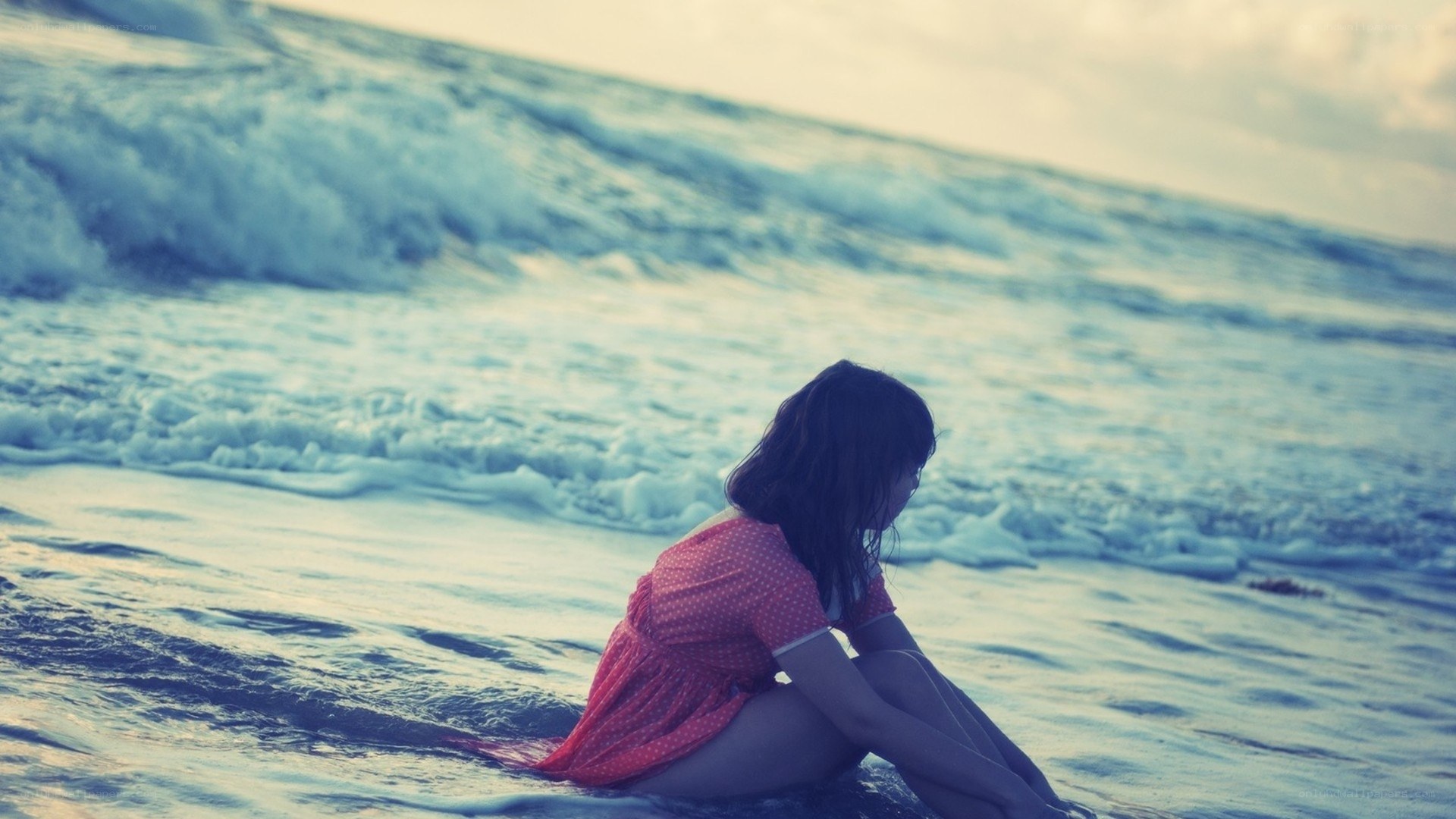 woman sitting on beach at sunset