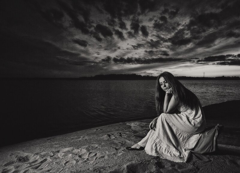 Woman Sitting on Beach — Black, Dramatic, Sunset