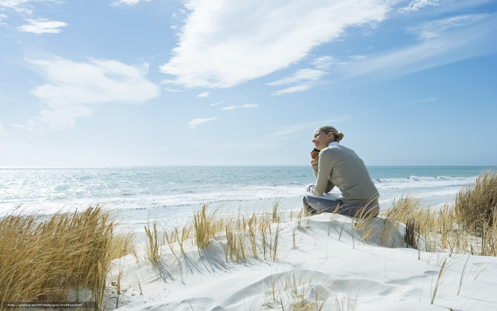 Woman sitting on beach dune