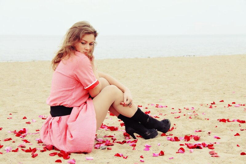 woman sitting on beach with rose petals