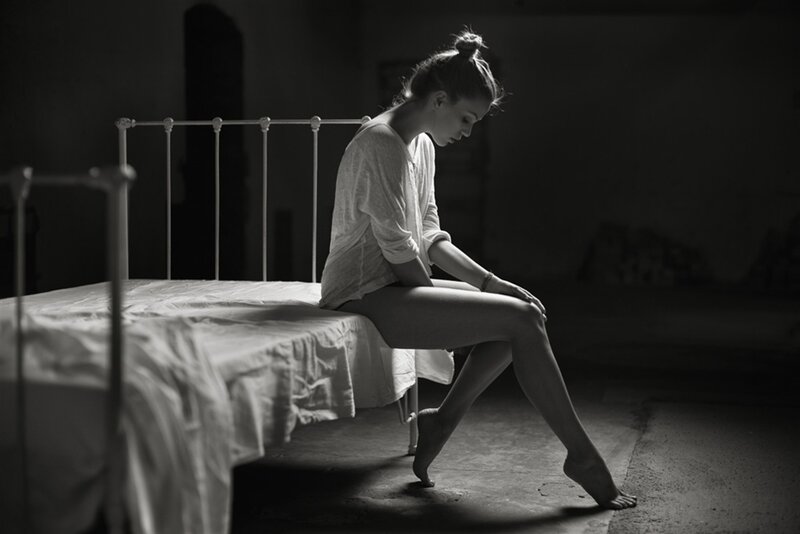 Woman Sitting on Bed — Black, Dramatic, Photograph, Floor