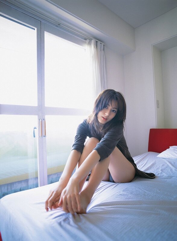 woman sitting on bed by window