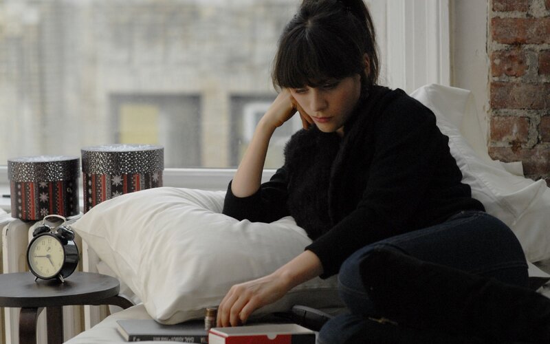 woman sitting on bed with books