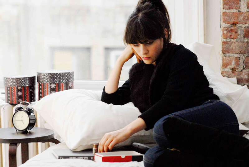 woman sitting on bed with books