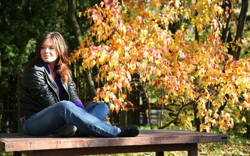 Woman sitting on bench in autumn