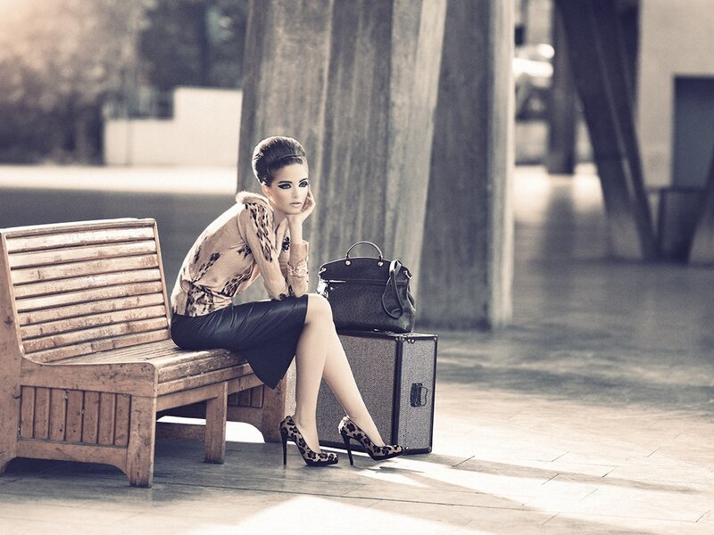 woman sitting on bench with suitcase