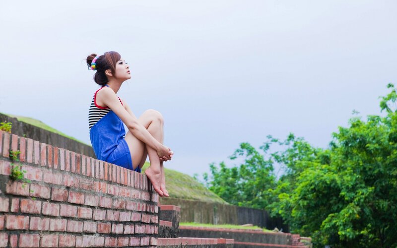 woman sitting on brick wall