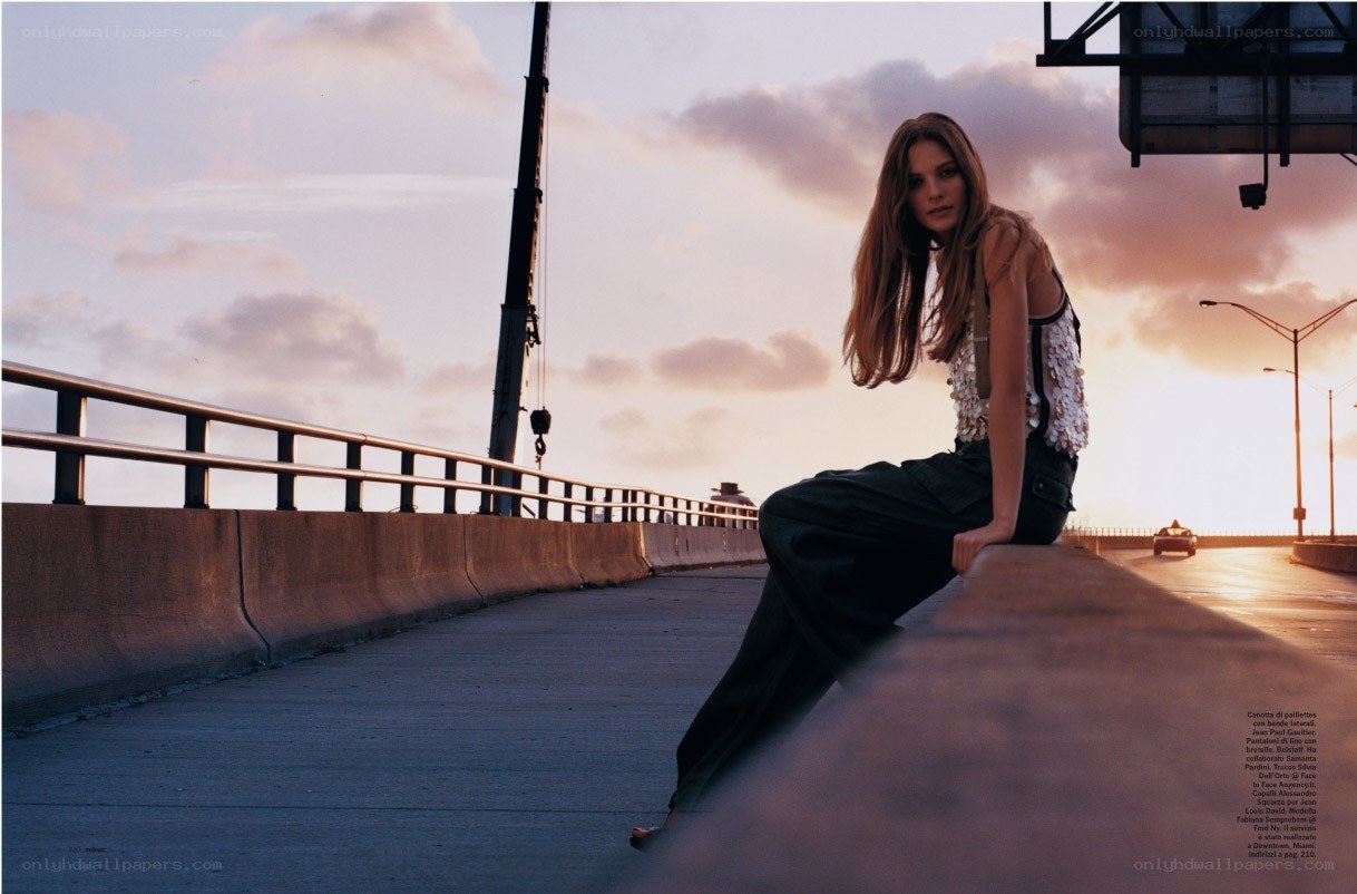 woman sitting on bridge at sunset