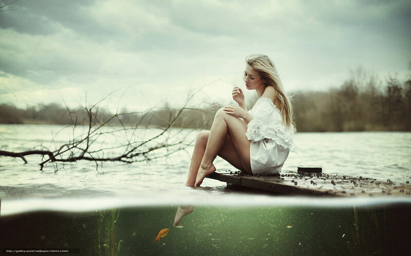 woman sitting on dock by lake