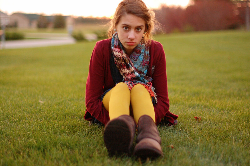 woman sitting on grass at sunset