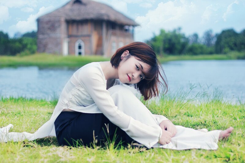 woman sitting on grass by lake