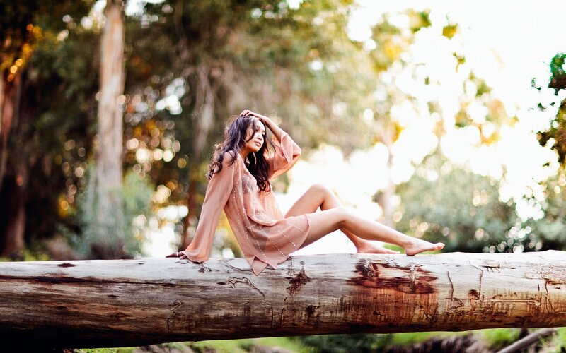 woman sitting on log in forest