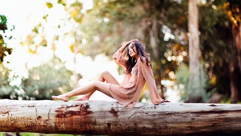 woman sitting on log in forest