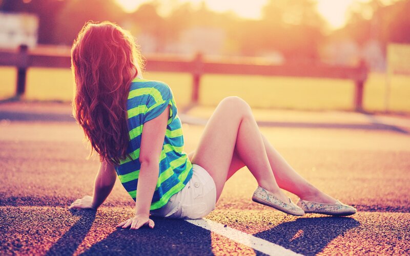 woman sitting on pavement at sunset